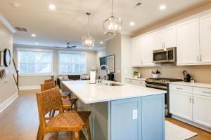 a kitchen with white cabinets and a kitchen island with chairs at Cozy South Carolina Abode - Steps from Main Street in Greenville