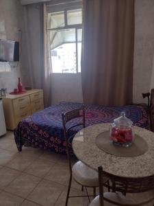 Zimmer mit einem Tisch und einem Bett sowie einem Tisch und Stühlen in der Unterkunft Loft encantador centro Guarapari in Guarapari