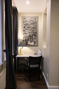 Habitación con escritorio con silla y pintura en Rein Klassik Hotel en Bad Pyrmont