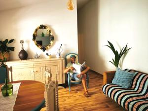 un homme assis sur une chaise en lisant un livre dans l'établissement Vida à portuguesa, Charming apartment "Algarve" , in the cultural and historical center, à Portimão