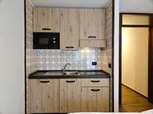 eine Küche mit Holzschränken und einem Waschbecken in der Unterkunft Hostdomus - City Center Apartment in Sestriere