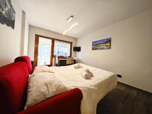 ein Schlafzimmer mit einem Bett und einem roten Sofa in der Unterkunft Hostdomus - City Center Apartment in Sestriere