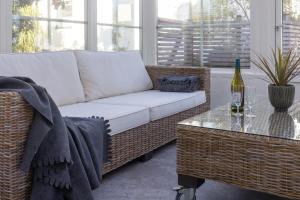 a living room with a wicker couch and a table at Villa Verde Österlen in Glemminge