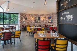 a restaurant with wooden tables and yellow and red chairs at Delta Hotels by Marriott Newcastle Gateshead in Newcastle upon Tyne