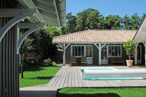 um quintal com uma piscina e uma casa em La villa aux oiseaux em Andernos-les-Bains