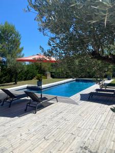 a pool with two chairs and a table and an umbrella at Maison proche du pic Saint Loup in Saint-Jean-de-Cuculles
