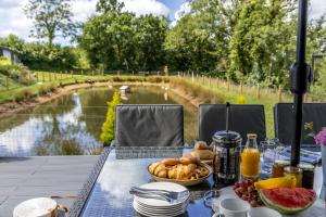 a picnic table with food and a view of a river at Maple Lodge, 20 Roadford Lake Lodges in Lifton