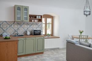 a kitchen with green cabinets and a couch in a room at Berkenyeliget Vendégház in Szigliget