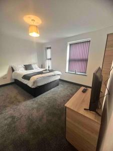 a bedroom with a bed and a flat screen tv at Gilman House in Stoke on Trent
