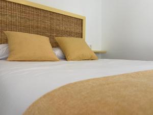 Una cama con dos almohadas encima. en Mamavira Hospedaje, en Meaño