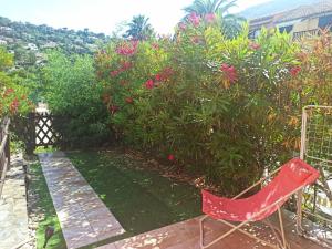 a red chair sitting in front of a garden at Appartement avec piscine in Cavalaire-sur-Mer