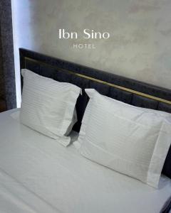twee kussens op een bed met een hotelbord erop bij Ibn Sino Hotel in Bukhara