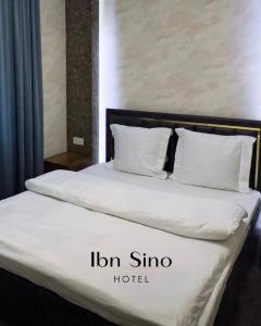 een bed met witte lakens en kussens in een kamer bij Ibn Sino Hotel in Bukhara