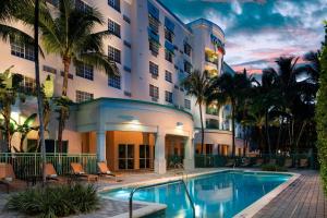 a hotel with a swimming pool in front of a building at Courtyard by Marriott Fort Lauderdale Airport & Cruise Port in Dania Beach