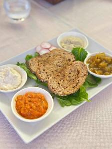 a plate of food with a sandwich and some dips at B&B Banatium in Tezze sul Brenta