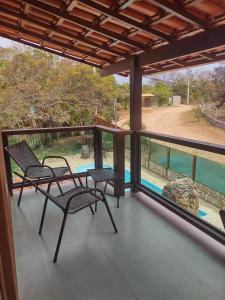 balcón con sillas y vistas a la piscina en Pousada Mangaba da Serra en Serra do Cipo