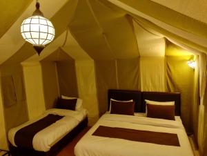 a bedroom with two beds in a tent at Khamlia Desert Luxury Camp in Merzouga