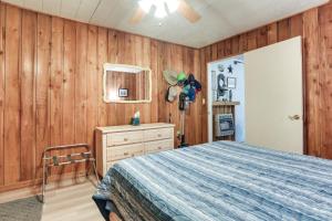 a bedroom with wooden walls and a bed and a dresser at Dog-Friendly Kingston Cabin with Wraparound Deck! in Kingston