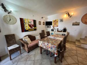 sala de estar con mesa, sillas y reloj en Villetta Calasetta intera casa vacanze, en Calasetta