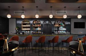 a bar in a restaurant with orange chairs and lights at Leonardo Hotel Galway in Galway