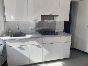 a white kitchen with a stove and a sink at Charmante petite maison à Olne in Olne
