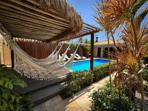 a hammock on a deck next to a swimming pool at Pousada Oasis Paracuru in Paracuru