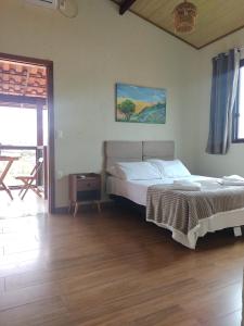 1 dormitorio con 1 cama y suelo de madera en Pousada Mangaba da Serra, en Serra do Cipo
