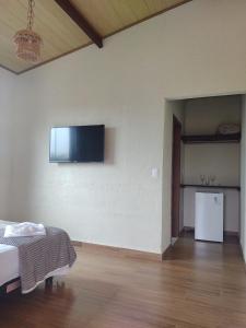 Habitación con cama y TV en la pared. en Pousada Mangaba da Serra en Serra do Cipo