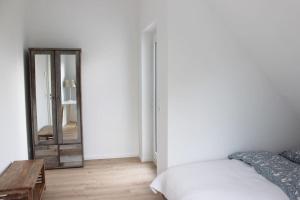 a white bedroom with a bed and a mirror at Beautiful terrace apartment in Bad Soden in Bad Soden am Taunus