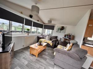 a living room with two couches and a tv at Wigbay Loch View 28 in Kirkcolm