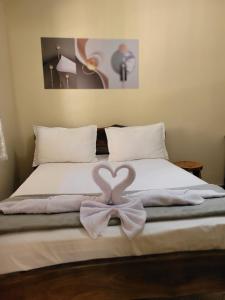 a bed with a heart shaped towel on it at Suítes Boa Viagem in Pirenópolis