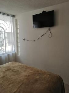 1 dormitorio con 1 cama y TV en la pared en (1) Cuarto confortable en la zona de Angelópolis. en Tlaxcalancingo