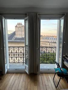 um quarto com duas grandes janelas com vista para a cidade em Appartement au pied de Montmartre / Jules Joffrin em Paris