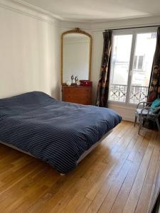 um quarto com uma cama e um espelho num piso de madeira em Appartement au pied de Montmartre / Jules Joffrin em Paris