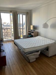 um quarto com uma cama num quarto com janelas em Appartement au pied de Montmartre / Jules Joffrin em Paris