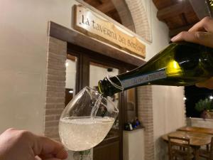Il Tripode - Le Dimore del Bordone في Vallo di Nera: شخص يصب زجاجة من النبيذ في كأس