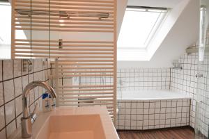 uma casa de banho com um lavatório, uma banheira e uma janela em Remark Studios - Wohnung für 6 in Großburgwedel em Burgwedel