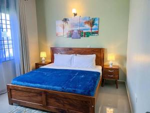 a bedroom with a large wooden bed with blue sheets at Cozy & tranquil 1 Bedroom dainty haven in Kampala in Buwate