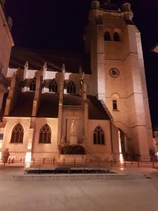 Un gran edificio con una torre de reloj por la noche. en La place aux fleurs, en Dole