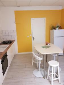 cocina con mesa blanca y 2 taburetes en La place aux fleurs, en Dole