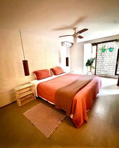 a bedroom with a large bed with an orange blanket at Casa da Arquiteta Guest House in Ilhabela