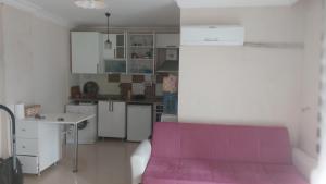 a kitchen with white cabinets and a pink couch at Gardenya rezidans 1+1 in Antalya