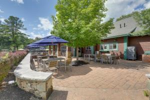 eine Terrasse mit Tischen und Stühlen und einem Sonnenschirm in der Unterkunft Inviting Summer Village Cottage Golf Cart and More! in Westford