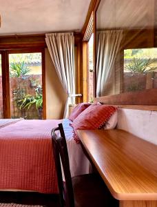 een slaapkamer met een bed en een houten tafel bij Casa da Arquiteta Guest House in Ilhabela