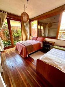 a bedroom with two beds and a large window at Casa da Arquiteta Guest House in Ilhabela