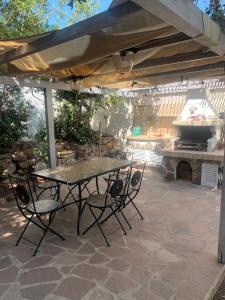eine Terrasse mit einem Tisch, Stühlen und einem Grill in der Unterkunft Villetta Calasetta intera casa vacanze in Calasetta