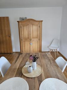 a wooden table with white chairs and a wooden cabinet at Ferienwohnung im schönen Allgäu in Biessenhofen