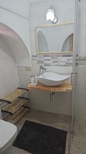 La salle de bains est pourvue d'un lavabo, d'un miroir et de toilettes. dans l'établissement TRULLO AURORA BOREALE, à Alberobello