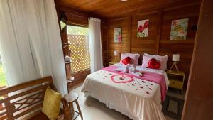 a bedroom with a large bed with red pillows at Pedacinho de Chão Chalés in Visconde De Maua