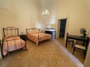 a bedroom with two beds and a table and a desk at Casa del Nonno Toto in San Pietro in Lama